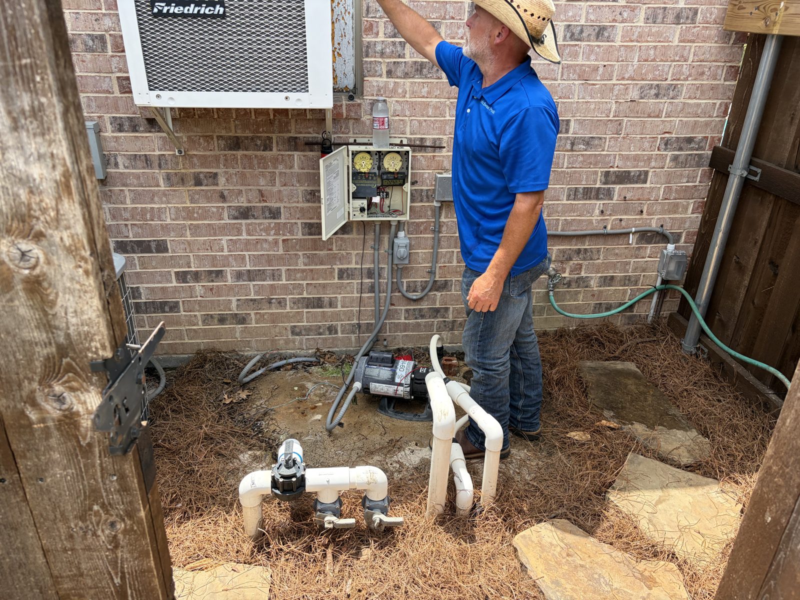 McEwan Pools servicing pool equipment and the wired electrical panel on the pad